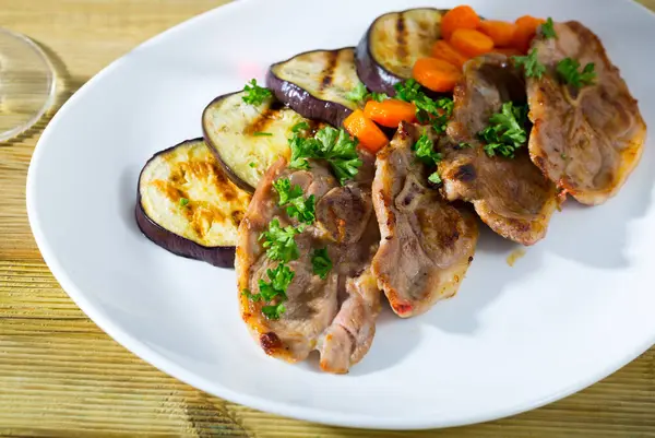 Tasty mutton loin chops grilled with eggplant slices and carrots garnished with fresh parsley