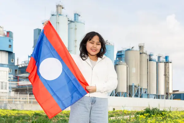 Fröhliche Junge Frau Steht Mit Großer Laotischer Flagge Vor Fabrikhintergrund — Stockfoto