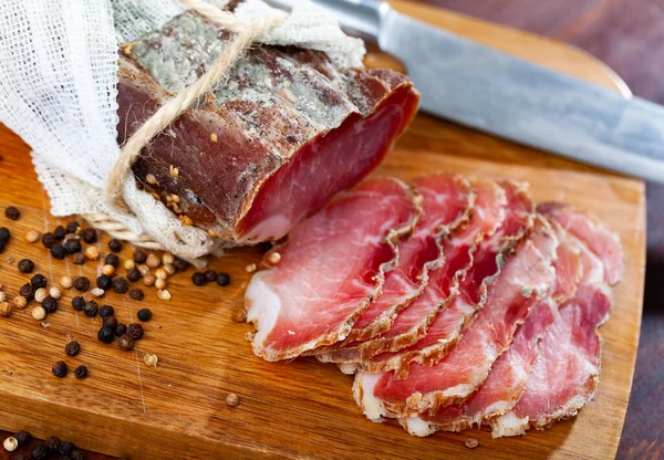Smoked pork tenderloin sliced on wooden cutting board. Cured pork meat.
