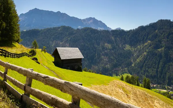 晴れた日 イタリアの岩のドロマイトの麓に緑豊かな牧草地に囲まれた素朴な木製のキャビンで風光明媚な夏の山の風景 — ストック写真