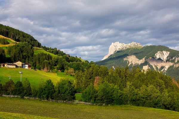 晴れた夏の日のイタリアのドロマイトの険しい岩の範囲に囲まれた緑のアルプス渓谷 緑豊かな牧草地 森林の丘と居心地の良い入植地の風景 — ストック写真