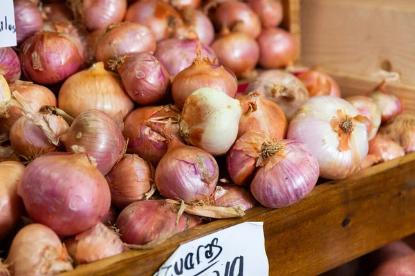 Close-up view of bulb onions placed in wooden box in outdoor grocery market