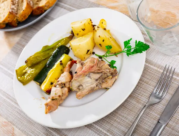 Portion of just cooked rabbit with vegetables. Rabbit meat garnished with potato, zucchini and bell pepper.