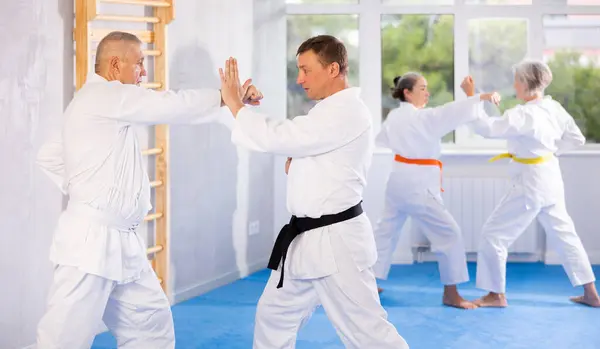 Intense oriental fight session, senior athletic practice combat karate techniques with male teacher, demonstrating agility and self-control in martial art single combat