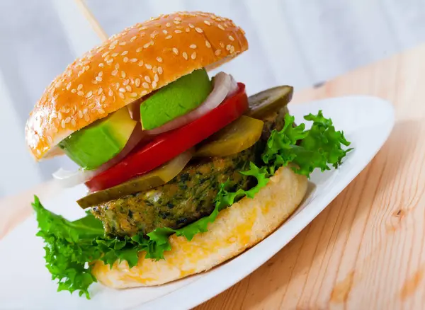 Delicious vegetarian hamburger with soybean patty, fresh vegetables and avocado at plate