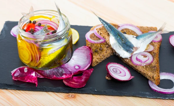 Homemade pickled anchovies with onions, beets, mix of peppers and marinade of vinegar, lemon, olive oil and sea salt. Served on black bread with onions