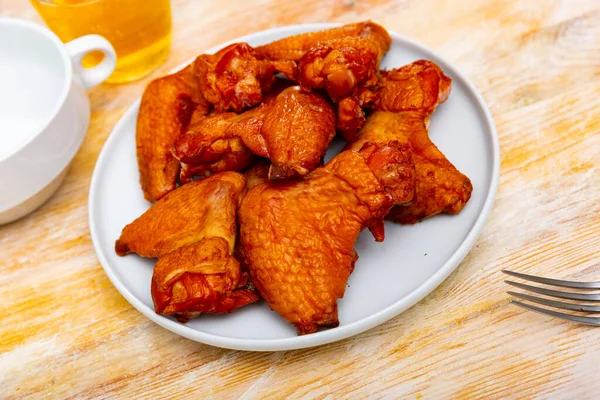 Appetizing smoked chicken wings dished up in a plate on the laid restaurant table