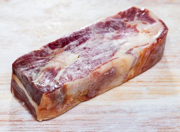 Piece of cured pork shoulder, traditional spanish lacon curado on wooden background