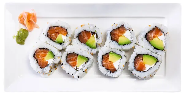 Sushi set - uramaki roll california is served on rectangular white plate. Traditional Japanese Asian cuisine, gastronomy. Isolated over white background