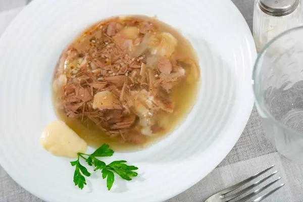 Popular Russian dish is a kholodets made from a jelly-like mass of chilled meat broth with pieces of meat. Decorated with ..fresh greenery and served with sauce