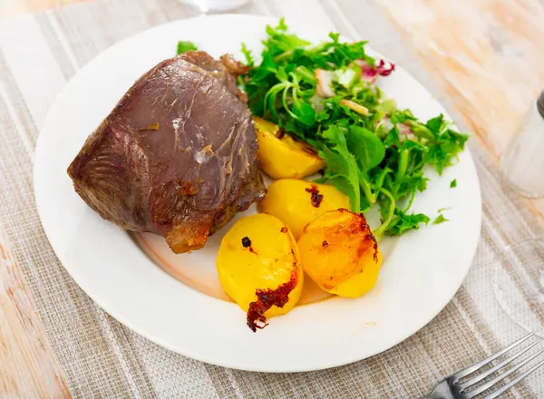 ジャガイモのスライスと新鮮な緑の野菜のガーニッシュを添えておいしい焼き牛肉の作品 — ストック写真