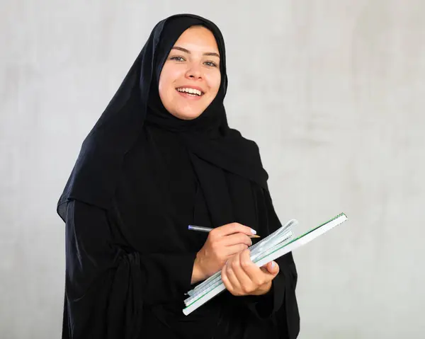 穿着伊斯兰传统服装拿着课本的年轻女生笑着 — 图库照片
