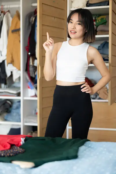 一位快乐的年轻亚洲女士站在衣橱前 决定选择哪一件衣服 — 图库照片