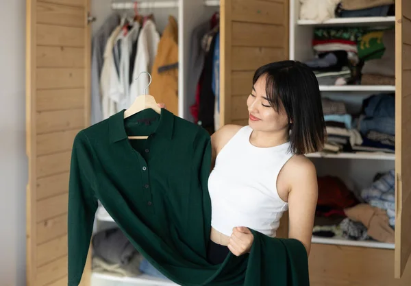 一位快乐的年轻亚洲女士站在衣橱前 决定选择哪一件衣服 — 图库照片