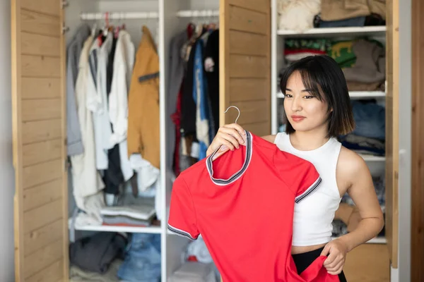 年轻的亚洲女人看到手里拿着的衣服在更衣室里选购时很高兴 — 图库照片