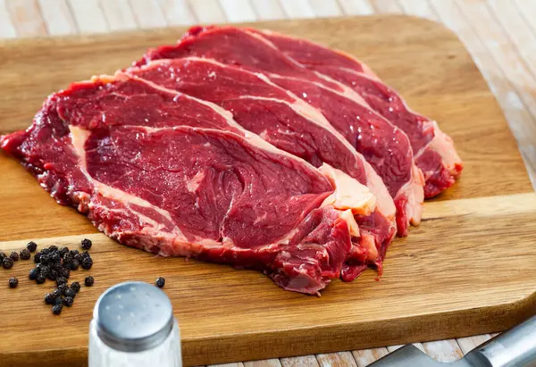 料理の材料 生の牛肉は 木製の表面にペパーコーンでエンテ — ストック写真