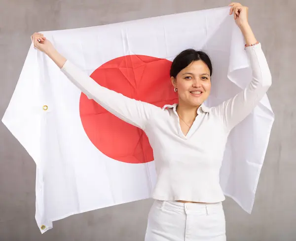 Smiling female fan of Japan cheers for winning holding a flag