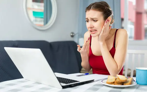 Girl with a sore ear complains to the doctor on the Internet using a laptop
