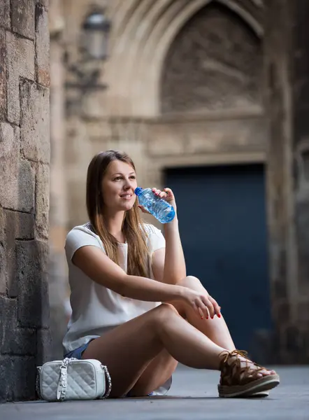 Glimlachende Jonge Vrouw Zit Buurt Van Oude Stenen Muur Drinkwater — Stockfoto