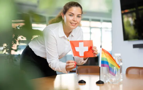 助理女孩为国际谈判和领导人会议准备办公室 Lady将Lgbt和瑞士的迷你国旗摆上桌 后续行动 — 图库照片