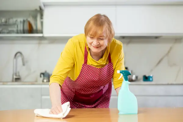 Önlüklü Yetişkin Bir Kadın Mutfak Masasını Paçavrayla Siliyor — Stok fotoğraf