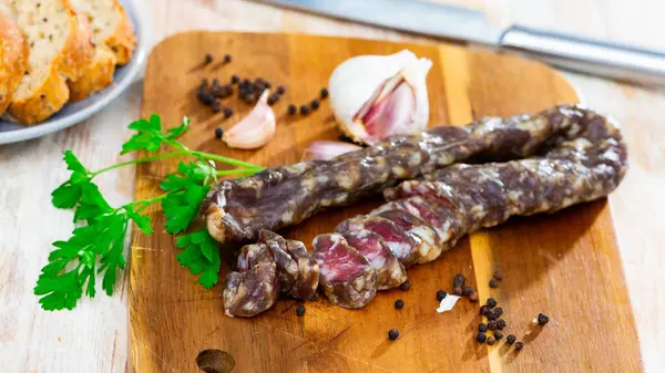 Thin Dry Pork Sausage Fresh Herbs Garlic Wooden Surface — Stock Photo, Image