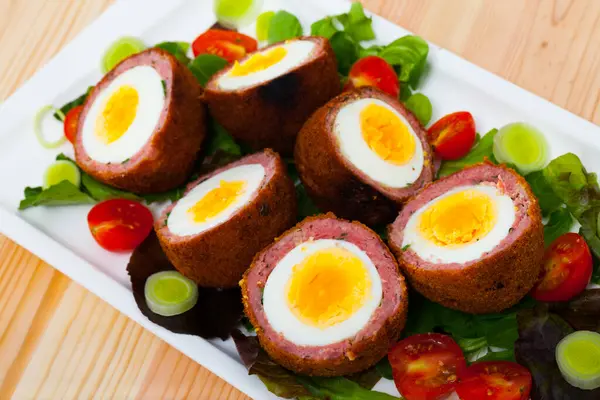 Dish of English cuisine - Scotch egg quail eggs served with greens and vegetables