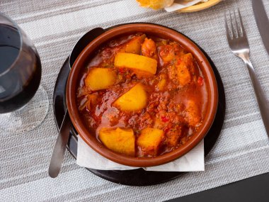 Plate of hearty and flavorful Patatas a la riojana, traditional Spanish dish of potatoes simmered with slices of chorizo sausage, pancetta, vegetables, spices and red wine clipart