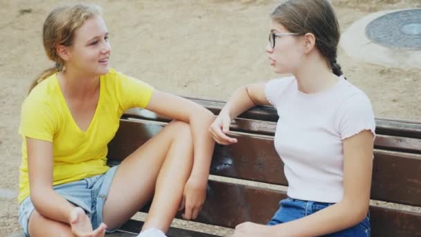 若いです女の子でショートパンツでベンチに座って何かを議論 — ストック動画