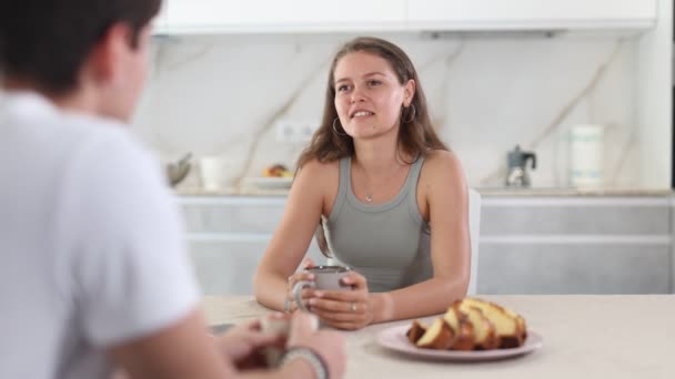 ポジティブな若者と女性は パイでお茶をしながらキッチンで楽しいコミュニケーションをとります — ストック動画