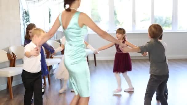 学校の部屋でフレンドリーな女性教師とセレブレーション学習サークルダンスのために服を着た19歳の生徒 女の子 男の子のクラス — ストック動画