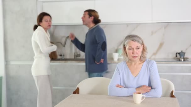 息子と妻の喧嘩の最中にキッチンに座っている 複雑な家族関係 義理の娘と夫はお互いに叫び合っている — ストック動画