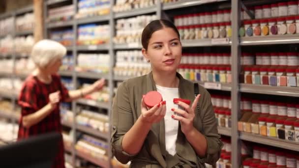 年轻女人买彩色油漆瓶子 — 图库视频影像