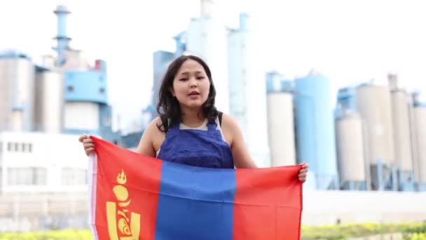 工場の背景にモンゴルの大きな旗を掲げている悲しい若い女性 高品質の4K映像 — ストック動画