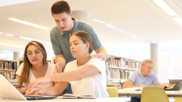 Genç Öğrenciler Kütüphanede Dizüstü Bilgisayarla Birlikte Çalışırlar Yüksek Kalite Görüntü — Stok video