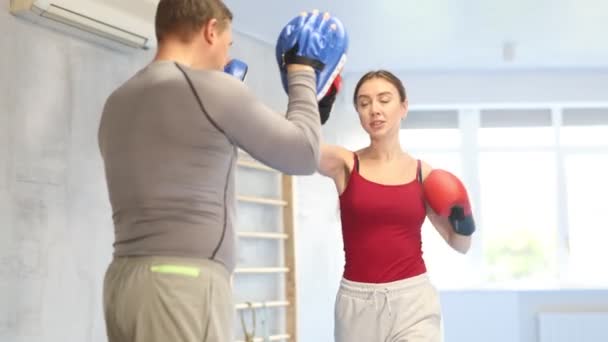 スポーツの女性はボックスに学ぶ パンチミットを打つ ジムでトレーナーと一緒にいる女性 高品質の4K映像 — ストック動画