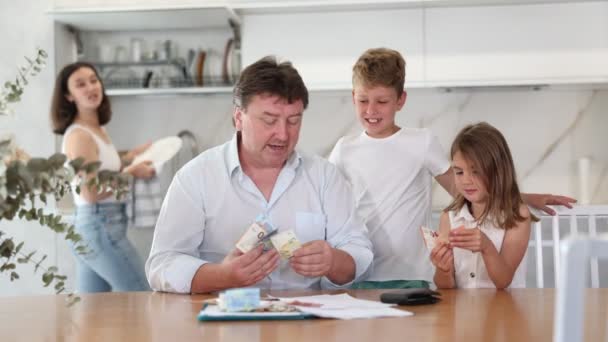 Усміхнений Тато Сидить Кухонним Столом Читає Оцінку Сімейних Доходів Рахує — стокове відео