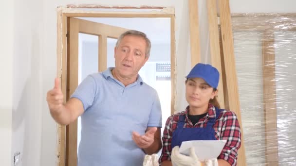 アパートのラテン語の女性の所有者とのドアの取付けを議論する男の労働者 — ストック動画