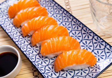 Sake nigiri - tasty dietary sushi with salmon and tuna, soy sauce closeup clipart