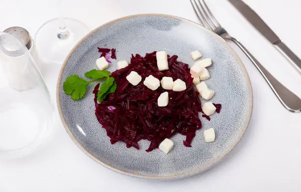 Healthy and easy-to-prepare appetizer for meat dishes is salad of stewed grated beetroot, seasoned with cheese cubes, and garnished with coriander sprigs.