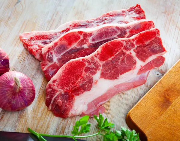 生牛肉 在厨房桌上放上油条 配上红葱 大蒜和欧芹 — 图库照片