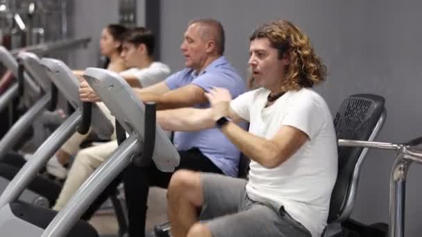 Άνδρες Και Γυναίκες Που Παρακολουθούν Εσωτερική Ποδηλασία Στο Γυμναστήριο Κάνοντας — Αρχείο Βίντεο