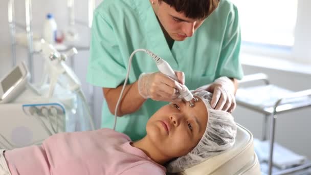 Jovem Cosmetologista Masculino Realiza Procedimento Microcorrente Facial Hardware Para Paciente — Vídeo de Stock