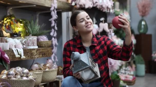 飾られたホールに立っている間 クリスマスの泡の材料をチェックする興奮した若い女性 — ストック動画