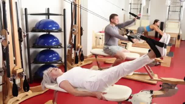 Elderly Woman Engaged Pilates Simulator Cable Ropes Stretching Leg Muscles — Stock Video