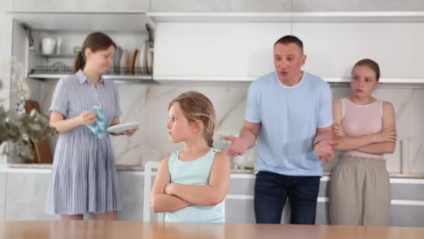在家里厨房里的女孩之间的沮丧的画像 交叉双臂皱着眉头 心怀不满的父母训斥她 却在模糊的背景下与大女儿站在一起 情感虐待概念 — 图库视频影像