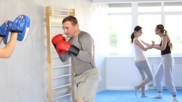 トレーニングセッション中にパンチダイトにキックを適用するボクシングコースの活発な成人男性実践者 高品質の4K映像 — ストック動画