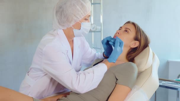 在美容院诊疗室 医生身穿制服 戴口罩 戴手套 为年轻女性病人注射美容品 — 图库视频影像