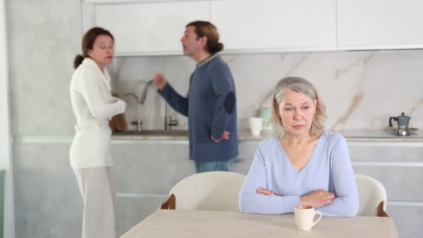 Расстроенная Старшая Женщина Сидит Кухне Время Ссоры Между Сыном Женой — стоковое видео