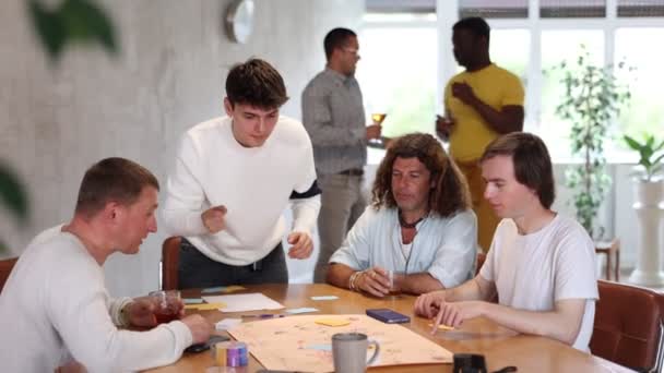 单身派对上 情绪愉悦的年轻人与不同国籍的男性朋友玩着有趣的棋盘游戏 — 图库视频影像